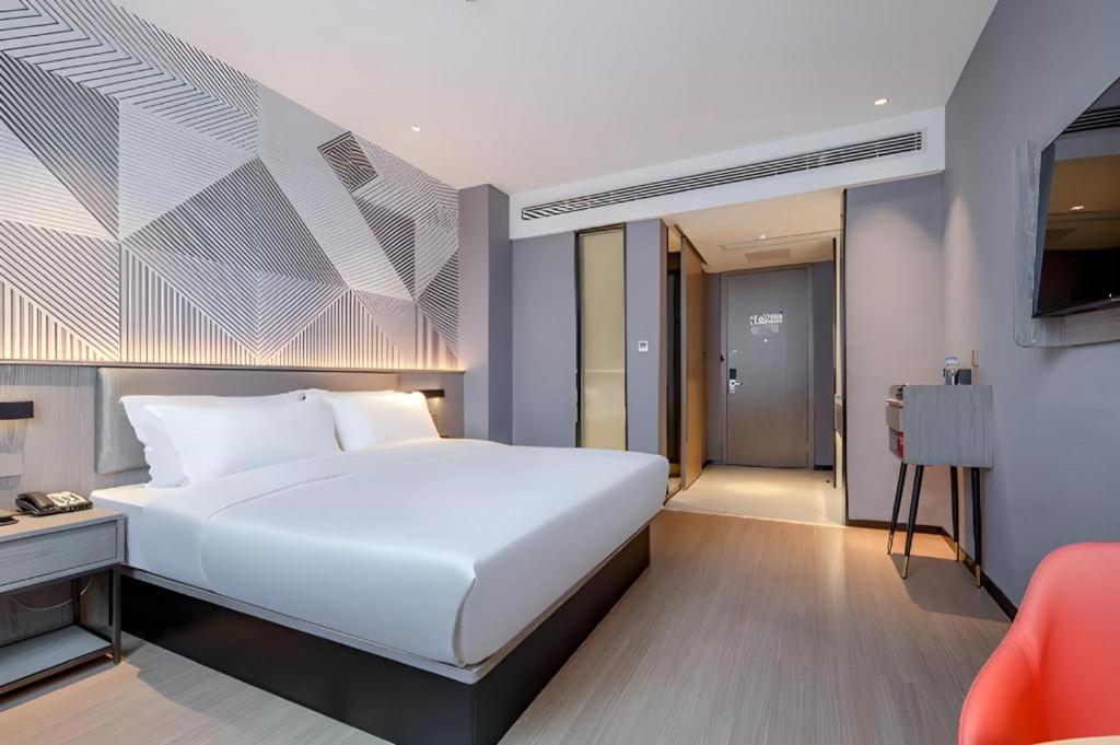 WuzhouにあるBorrman Hotel Wuzhou College Fumin Roadの大きな白いベッドとテレビのある寝室