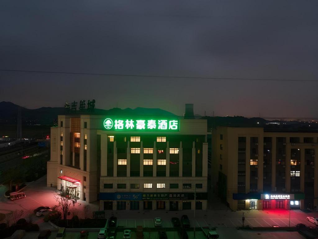 a building with a green sign on it at night at Green Tree Inn Zhejiang Ningbo Yuyao Haijixincheng Wholesales Market in Ningbo