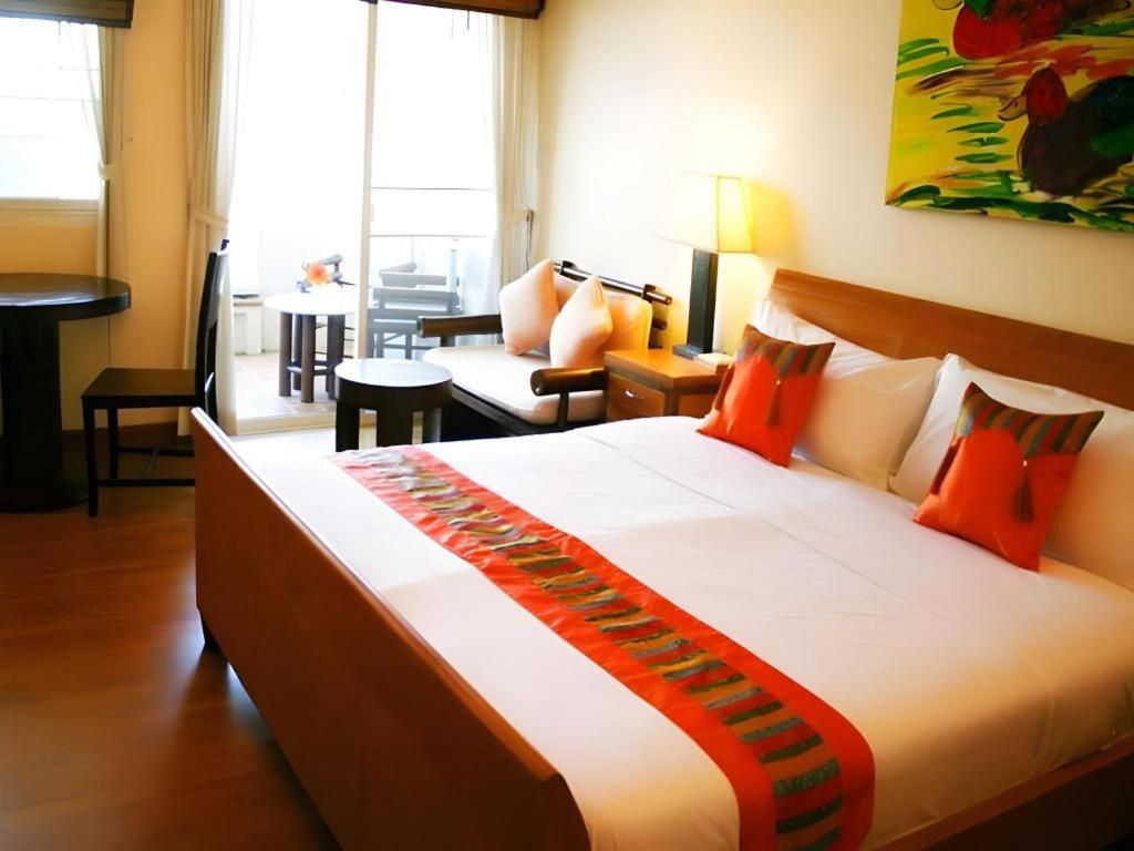 a hotel room with a large bed with orange pillows at Gerard Habitat Hotel in Chiang Mai