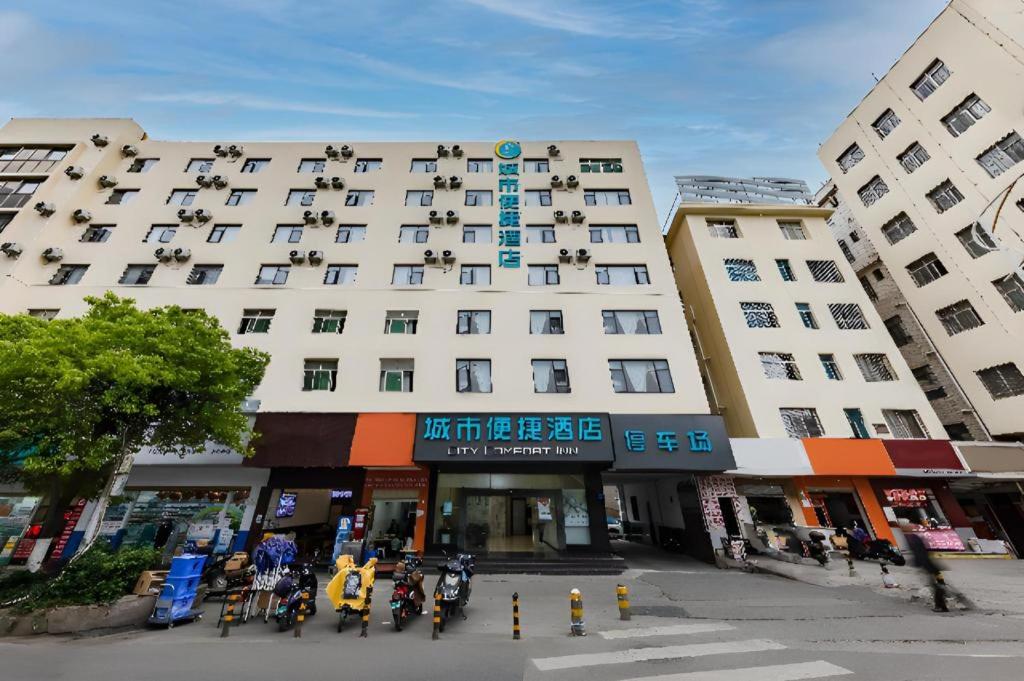 a large white building with people sitting outside of it at City Comfort Inn Kunming Dashuying Yejin Hospital Wangdaqiao in Kunming