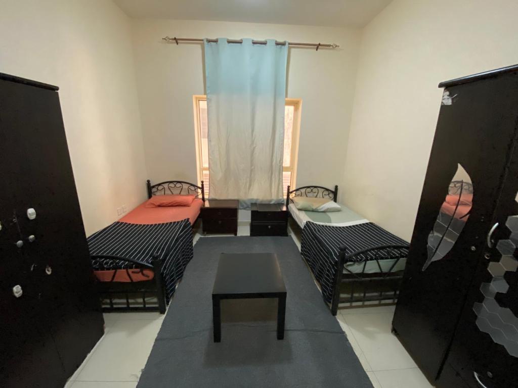 una camera con due letti e un tavolo di سكن شباب بالتعاون - ALEX Hostel - Sharjah a Sharjah