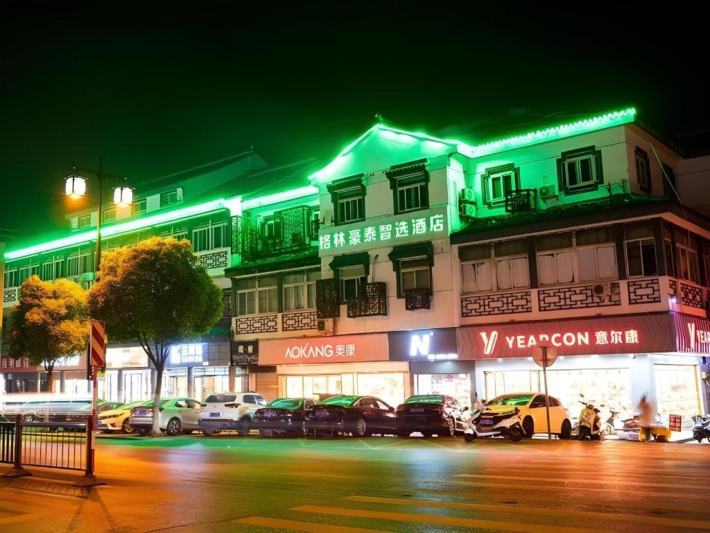 un edificio con auto parcheggiate di fronte ad esso di notte di GreenTree Inn Express Suzhou Luzhi Ancient Town Scenic Area Xiaoshi Road a Suzhou