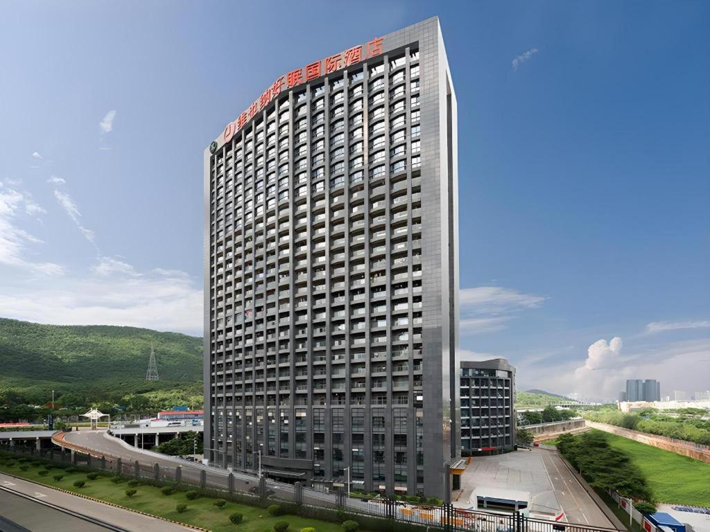 深セン市にあるBest Sleep International Hotel Shenzhen Tanglang Metro Stationの赤い看板が立つ高層ビル