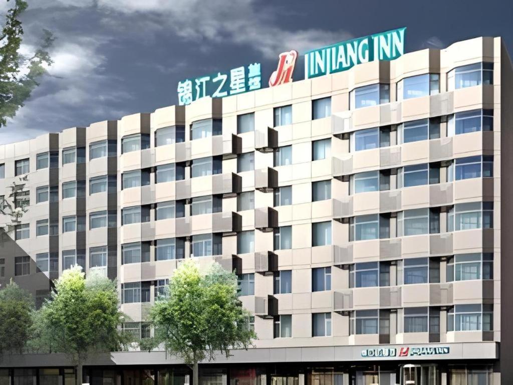 Jinjiang Inn Wuhan Wansongyuan Food Street Qushui Building في ووهان: مبنى ابيض كبير عليه لافته