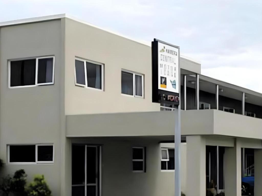 a white building with a sign in front of it at Hawera Central Motor Lodge in Hawera