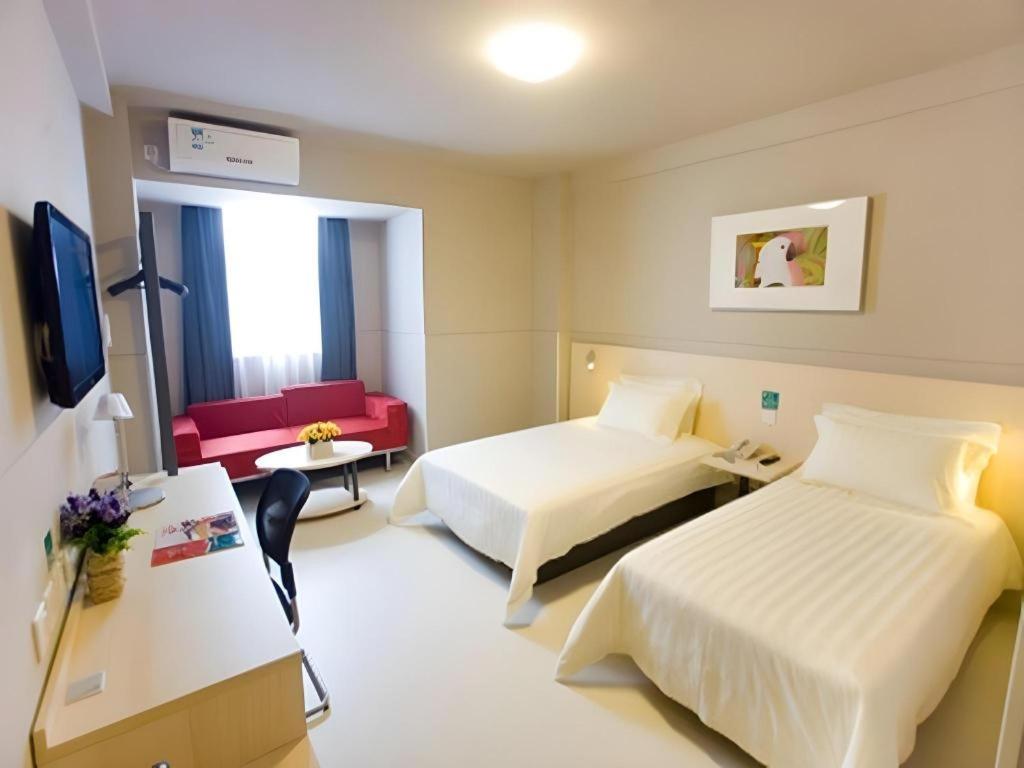 a hotel room with two beds and a red couch at Jinjiang Inn Sanya Hexi Road Pedestrian Bridge in Sanya