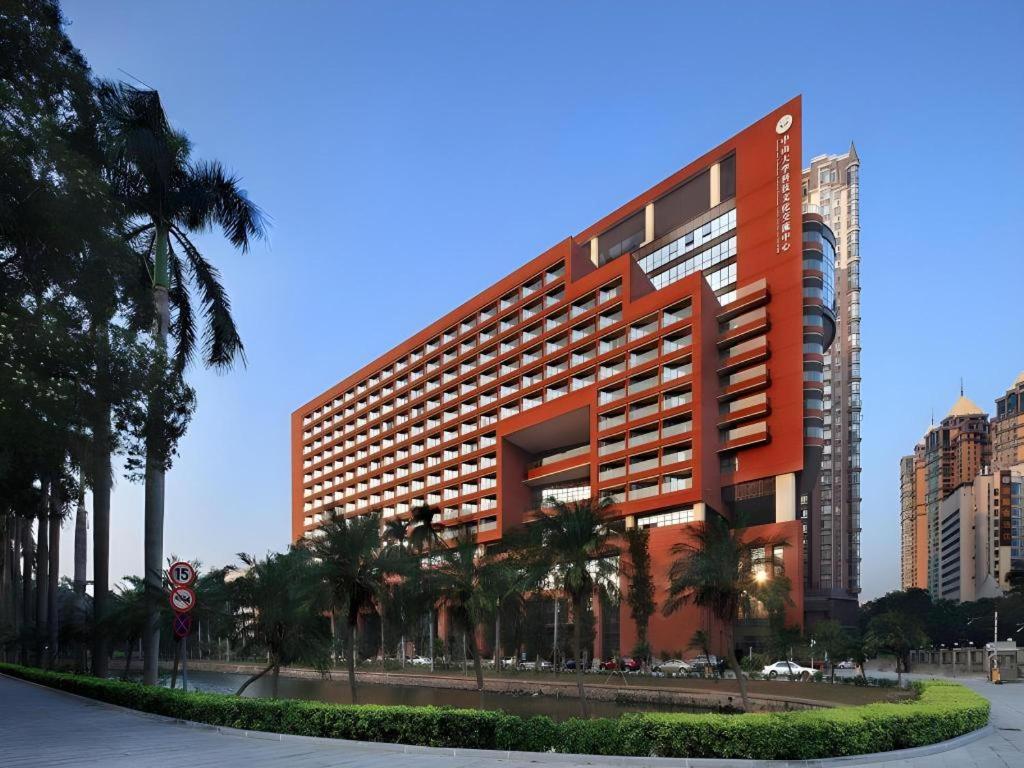 a large orange building with palm trees in front of it at SUN Yat-sen university Hotel and Conference Centre in Guangzhou