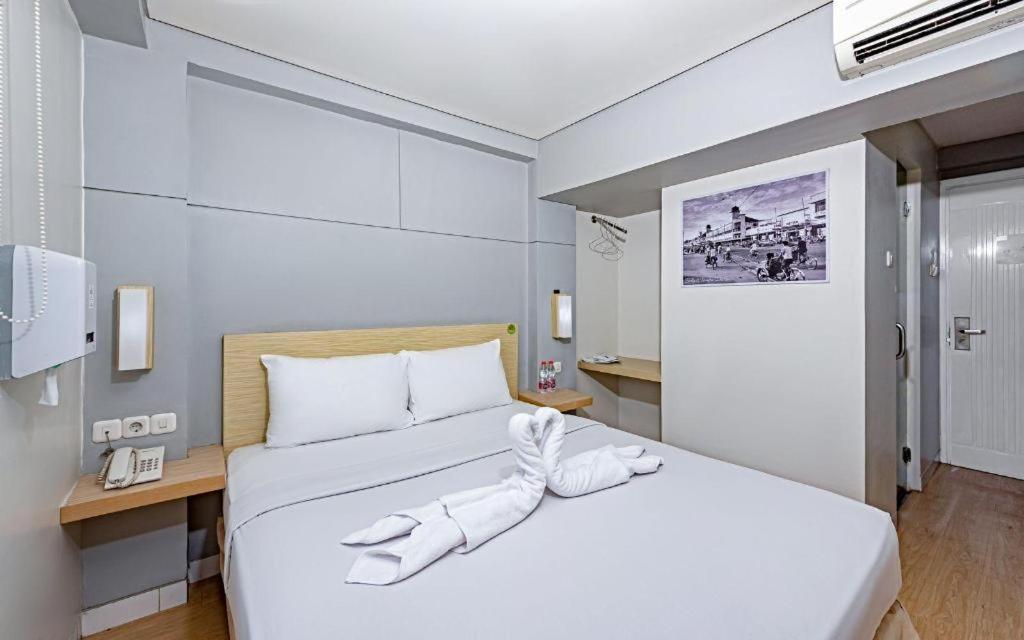 a hotel room with two beds with white sheets at IXO Bekasi in Bekasi