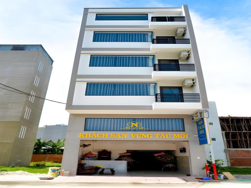 a tall white building with a sign in front of it at New Vung Tau Hotel in Vung Tau