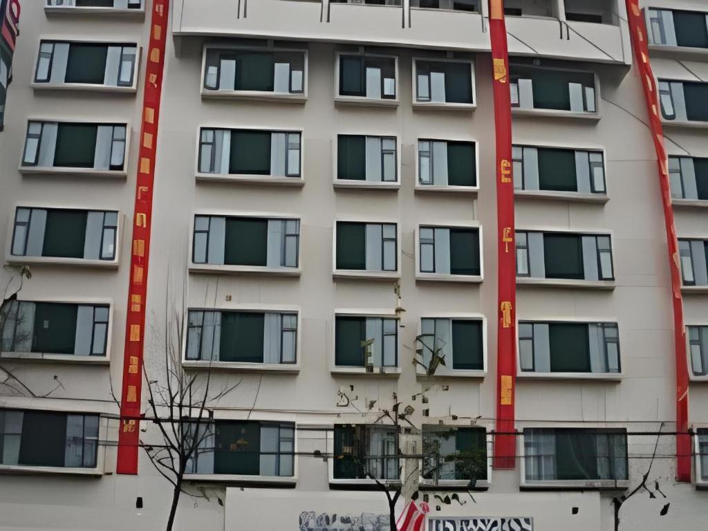a tall white apartment building with windows at Magnotel Business Xuzhou Jinying Sudi Road Metro Station in Xuzhou