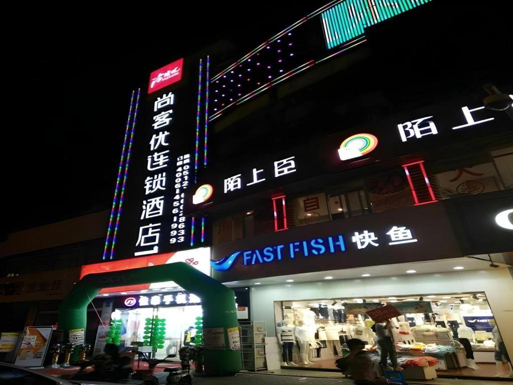 a building with a fast food restaurant with neon signs at Thank Inn Hotel Jiangsu Suzhou Luzhi Ancient Town Scenic Area in Suzhou