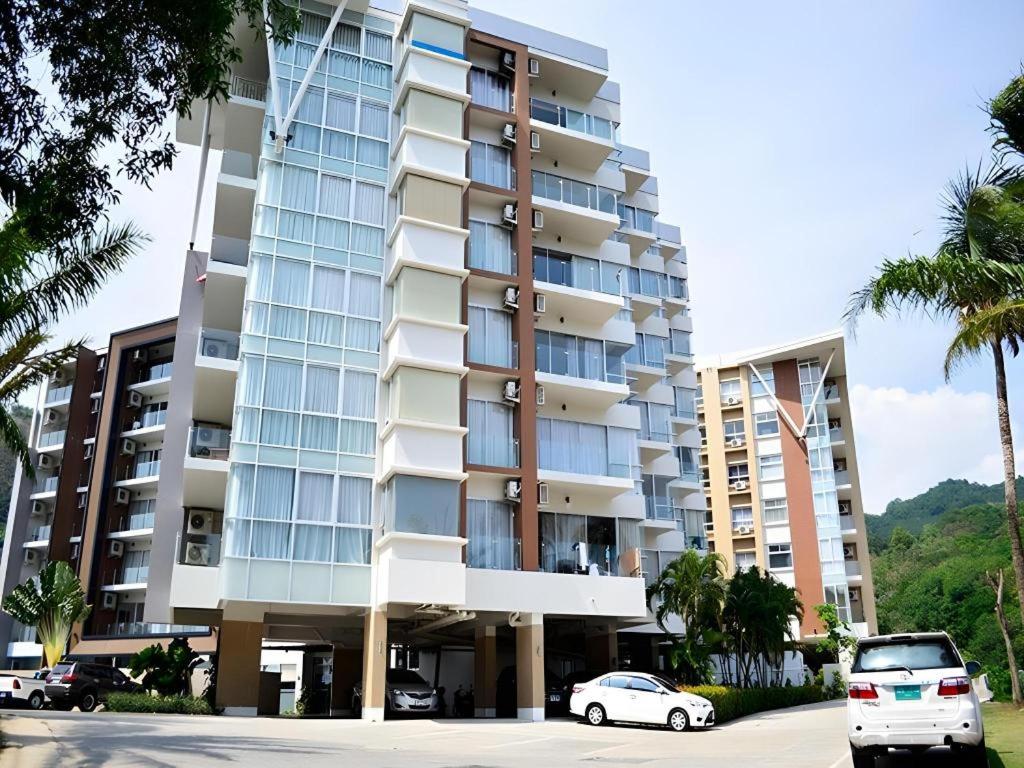 a large building with cars parked in front of it at Chic Residences at Karon Beach in Karon Beach