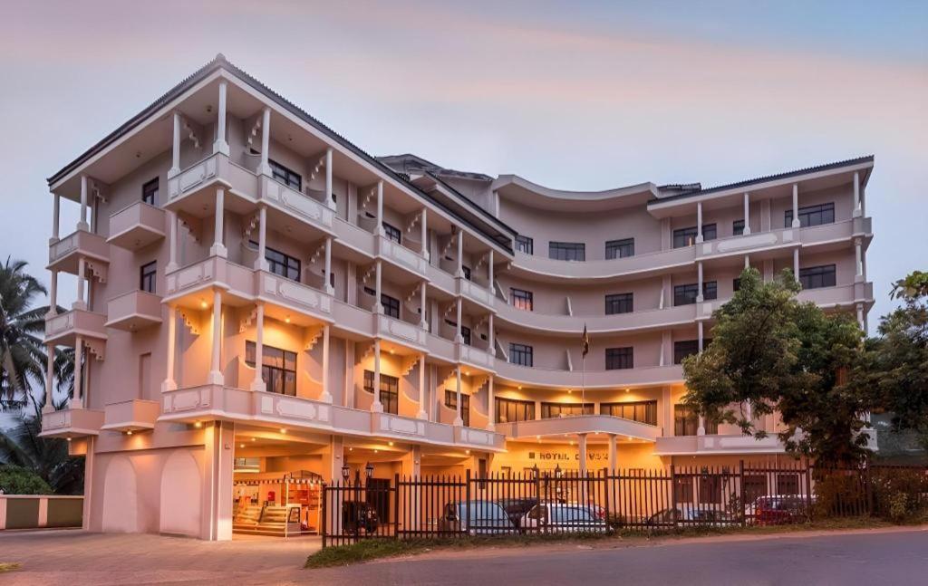 a large white building with cars parked in front of it at Devon Hotel in Kandy