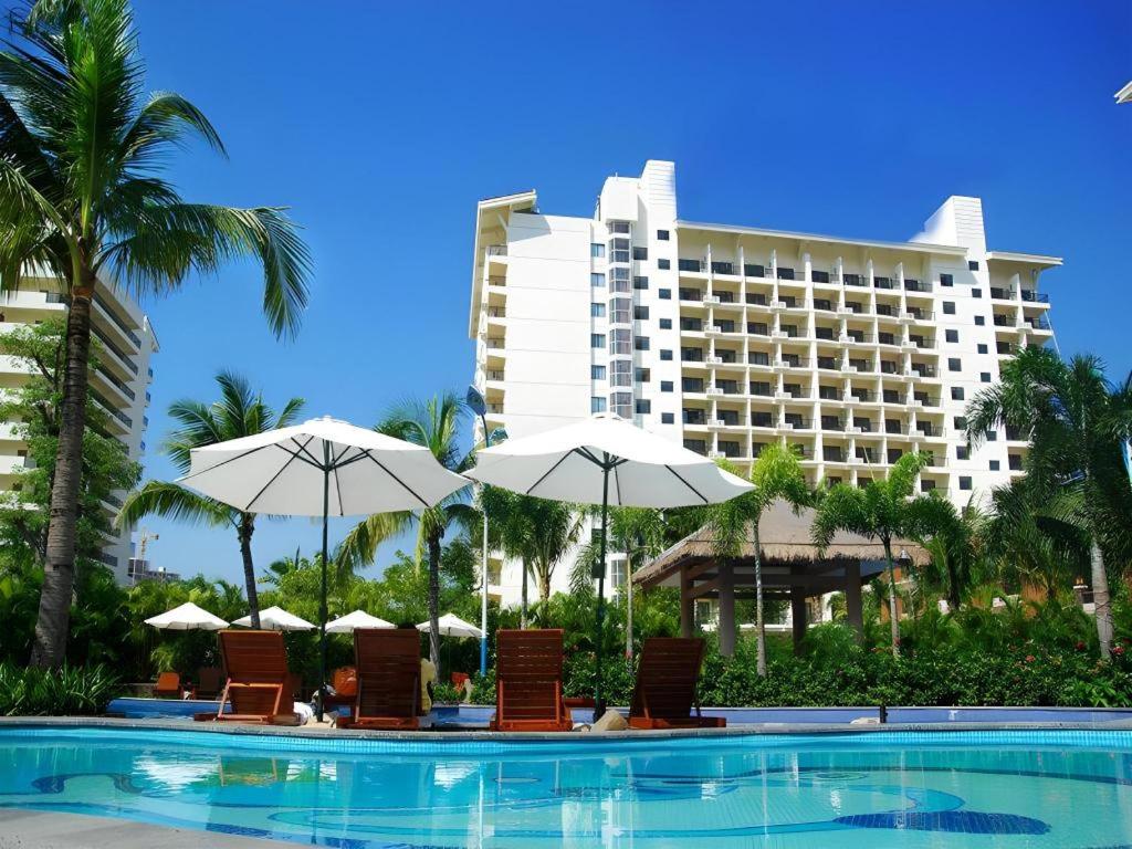 un hôtel avec des chaises et des parasols à côté d'une piscine dans l'établissement Yuhai International Resort Hotel, à Sanya