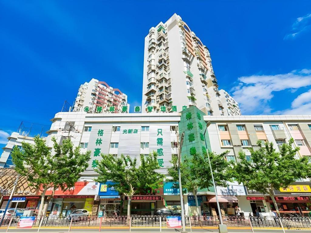 wysoki biały budynek z drzewami przed nim w obiekcie GreenTree Inn Shanghai Guangxin Road Tongji Hospital Express Hotel w Szanghaju