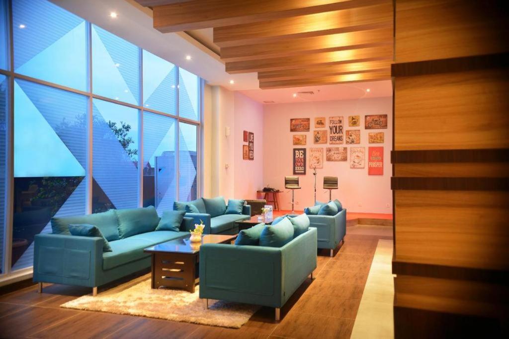 ein Wohnzimmer mit blauen Sofas und einem großen Fenster in der Unterkunft Ayola First Point Hotel Pekanbaru in Sultan Syarif Kasim II International Airport