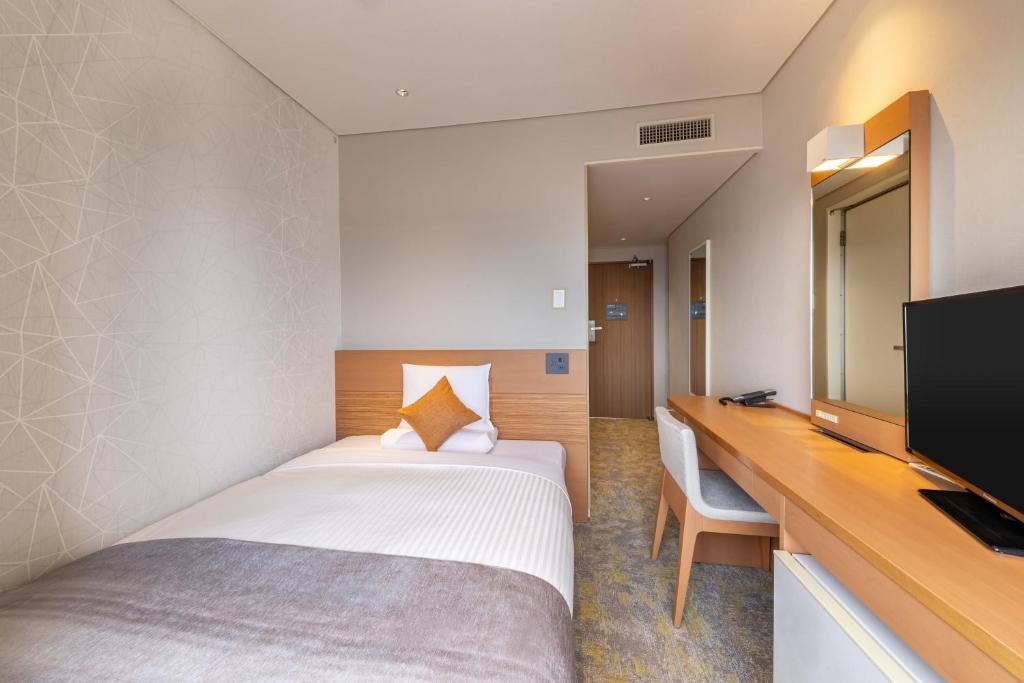 Una habitación de hotel con una cama, un escritorio y un televisor. en Art Hotel Niigata Station, en Niigata