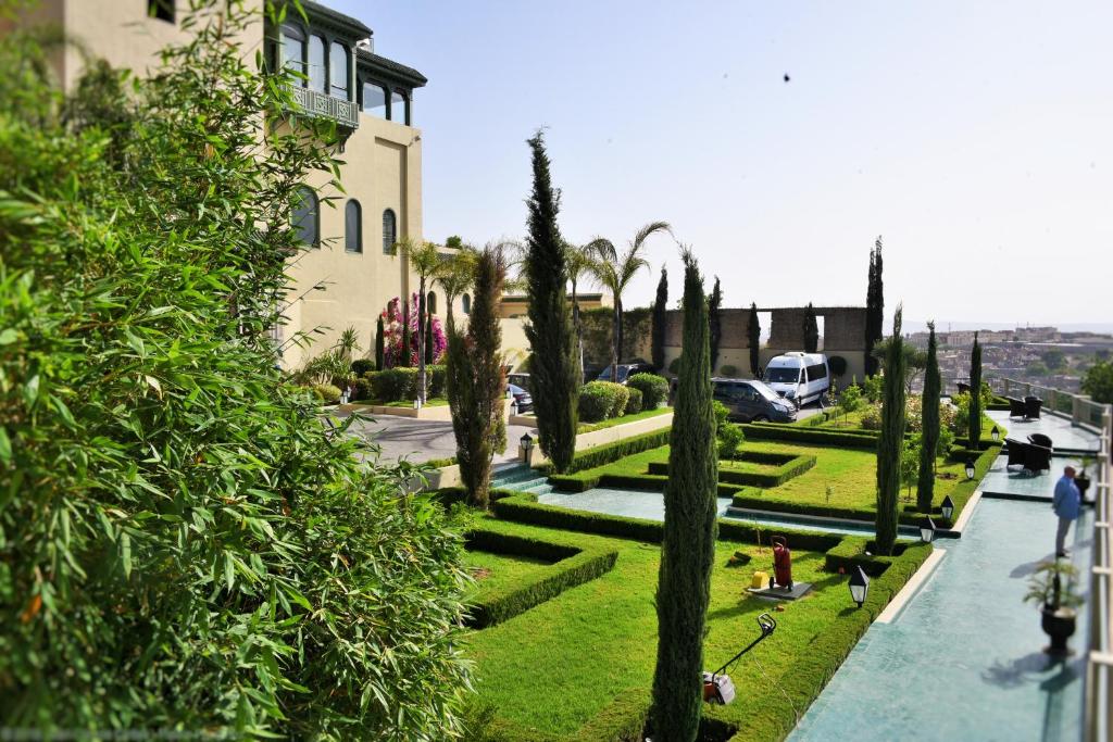 - une vue sur un jardin planté de palmiers et un bâtiment dans l'établissement Palais Faraj Suites & Spa, à Fès