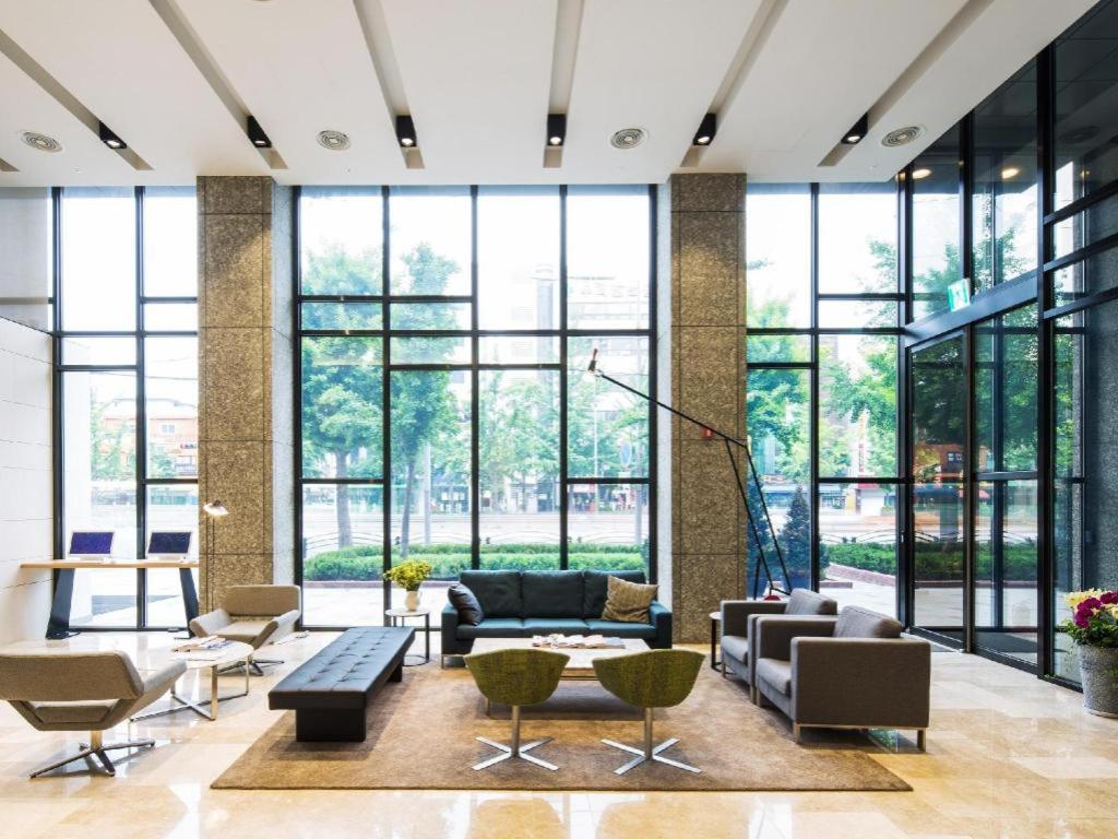 a lobby with large windows and couches and chairs at Hotel Denim Seoul in Seoul