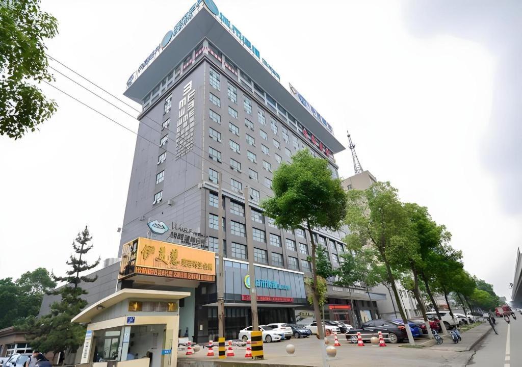 a tall building on a street with a parking lot at City Comfort Inn Jingzhou Ancient City Taiyue Road in Caoshi