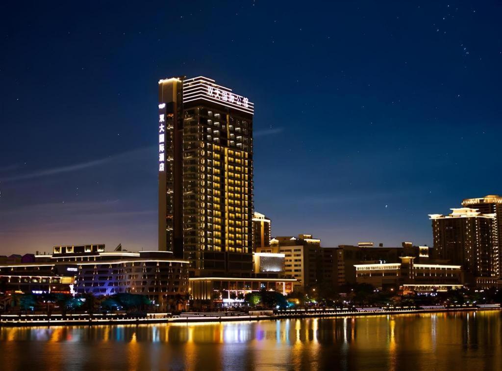 a city skyline with a tall building at night at Sanya Shuangda Adelaide In Resort Hotel in Sanya