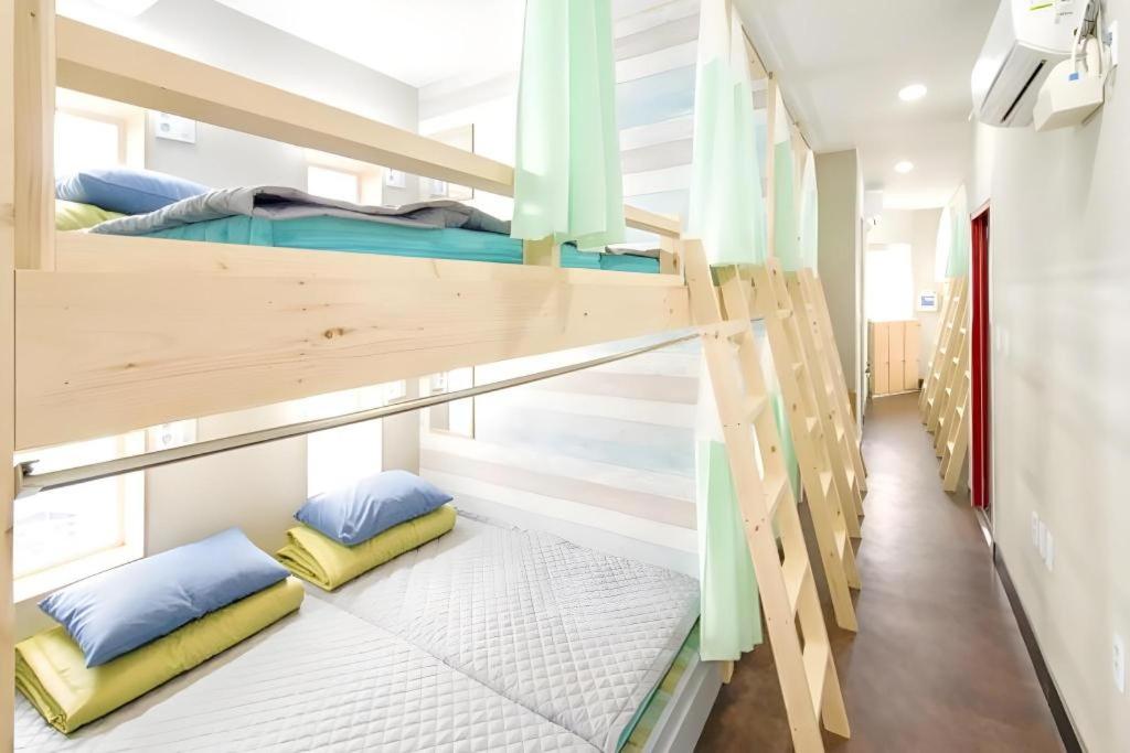 a bunk bed room with two bunk beds and pillows at Capsule Inn Gangneung in Gangneung