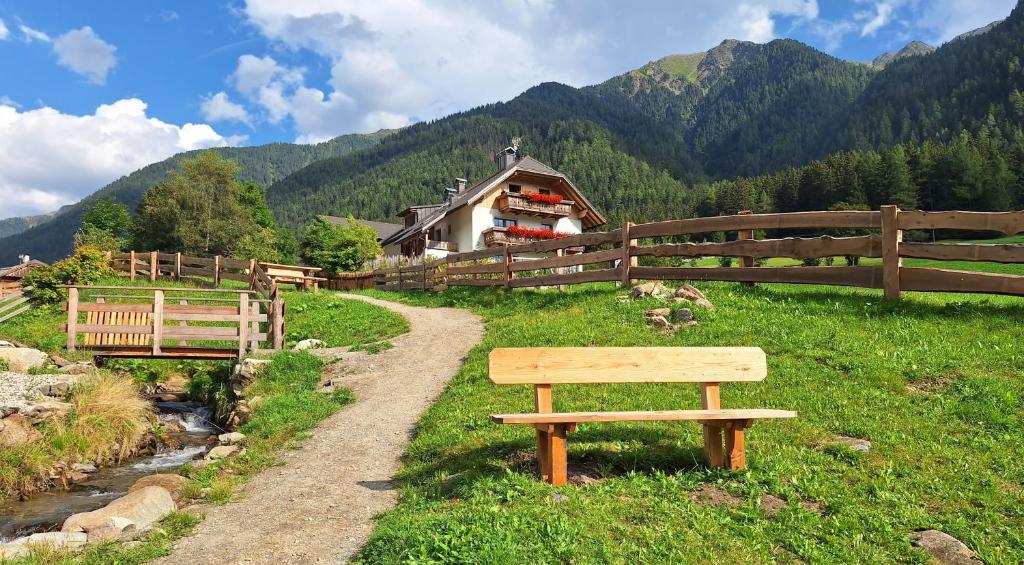 a wooden bench sitting in a field near a fence at Unterreinischhof in Anterselva di Mezzo