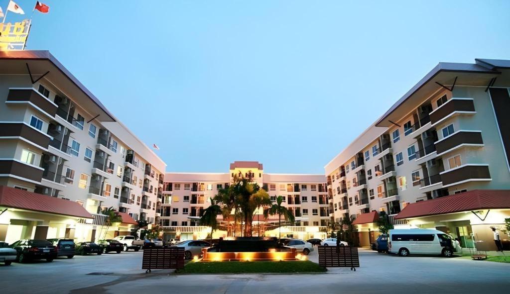a large apartment building with a fountain in a parking lot at The Residence Prachinburi in Si Maha Phot