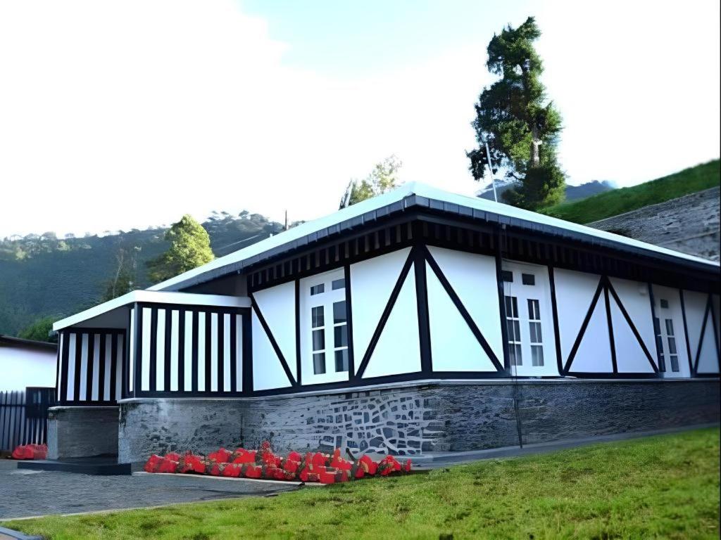 ein Haus mit roten Blumen davor in der Unterkunft 26 Loversleap Cottage in Nuwara Eliya