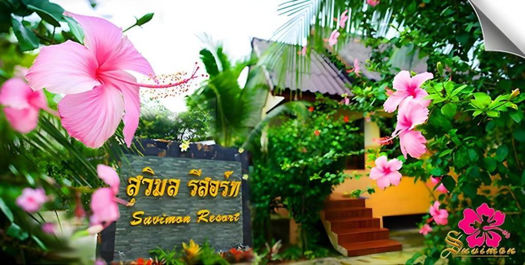 a sign in front of a garden with pink flowers at Suvimon Resort in Si Maha Phot