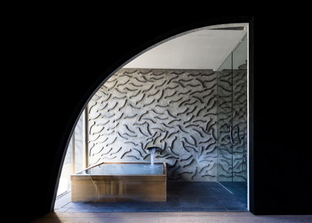 a room with a bath tub and a wall with a wall at Kimuraya in Kusatsu