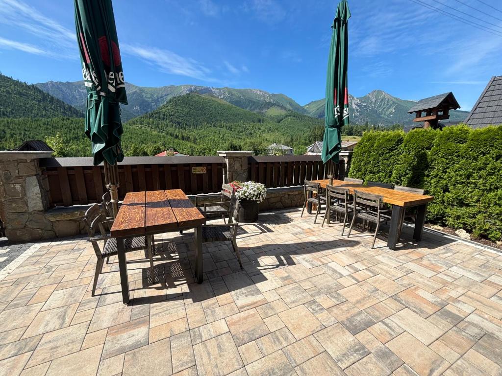two tables and chairs on a patio with mountains in the background at Penzion TATRY Restaurant GORAL in Ždiar