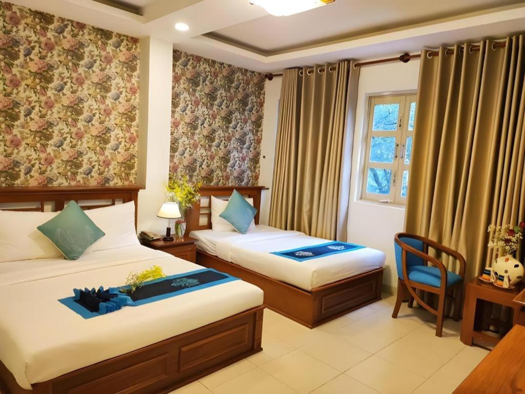 a hotel room with two beds and a window at Hồng Hạc hotel in Ho Chi Minh City