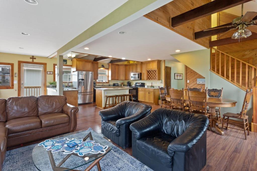 a living room with leather furniture and a kitchen at 6090 - Seas The Day NH in Nags Head