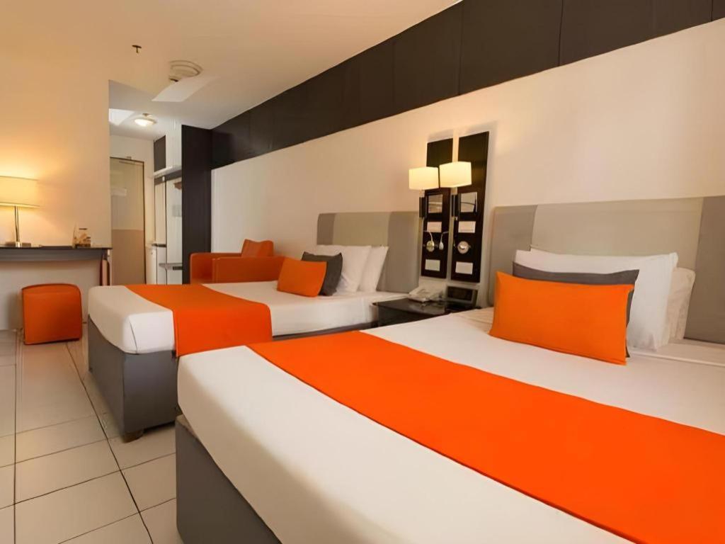 - 2 lits dans une chambre avec des tons orange et blanc dans l'établissement Majestic Hotel Manila - Formerly Octagon Mansion Hotel Manila, à Manille
