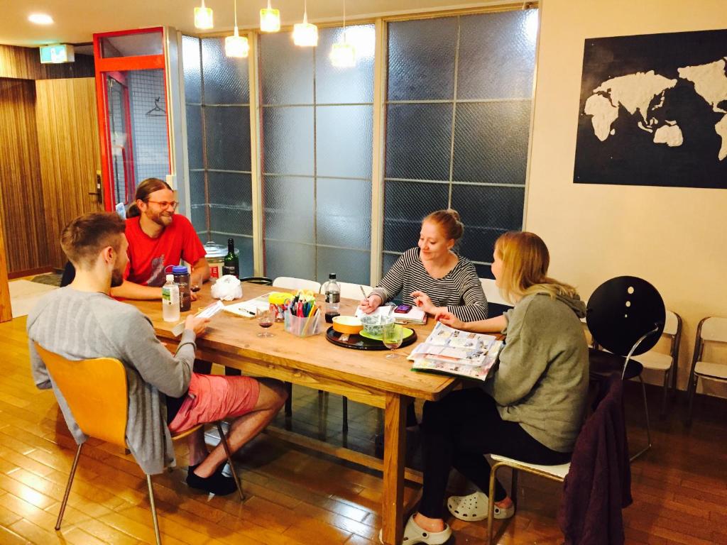 un grupo de personas sentadas alrededor de una mesa en The Evergreen Hostel 長期ステイ歓迎 エバーグリーンホステル, en Hiroshima