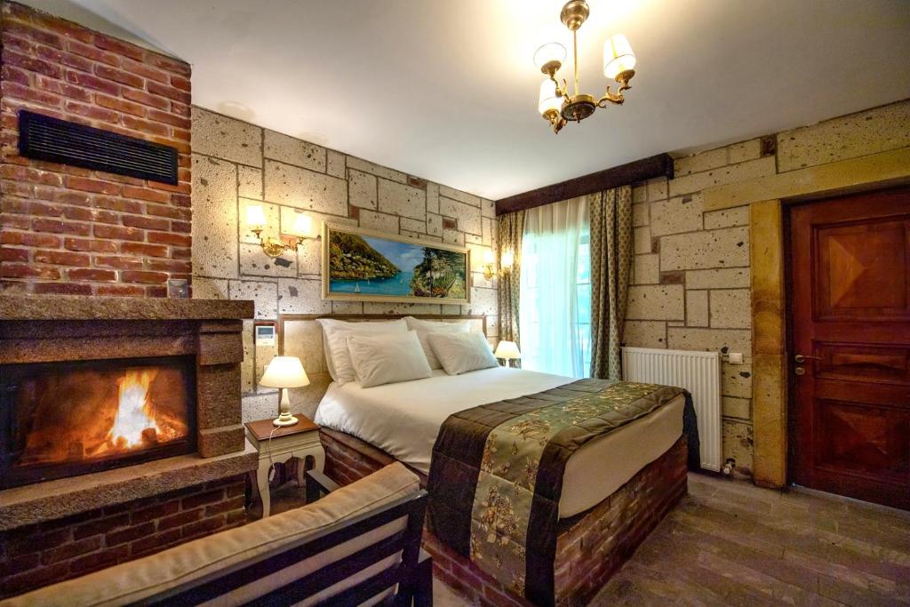 a bedroom with a large bed and a fireplace at Wineport Lodge Agva Riverside Hotel & Winery in Ağva