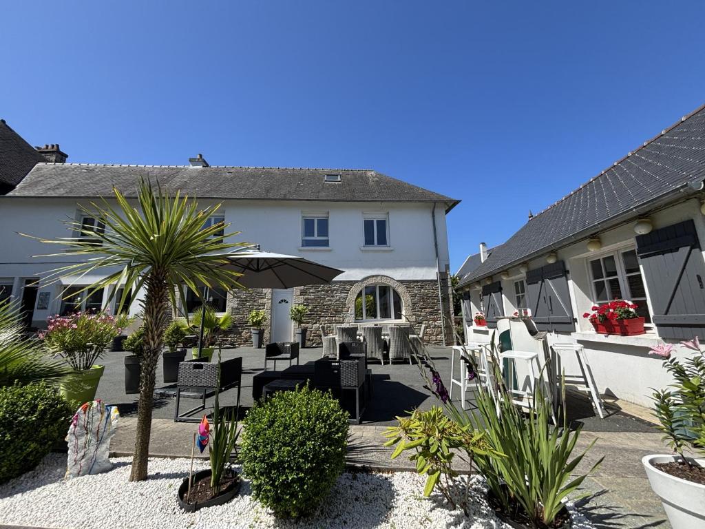 une terrasse avec des chaises et un parasol en face d'une maison dans l'établissement la maison du centre, à Lannion