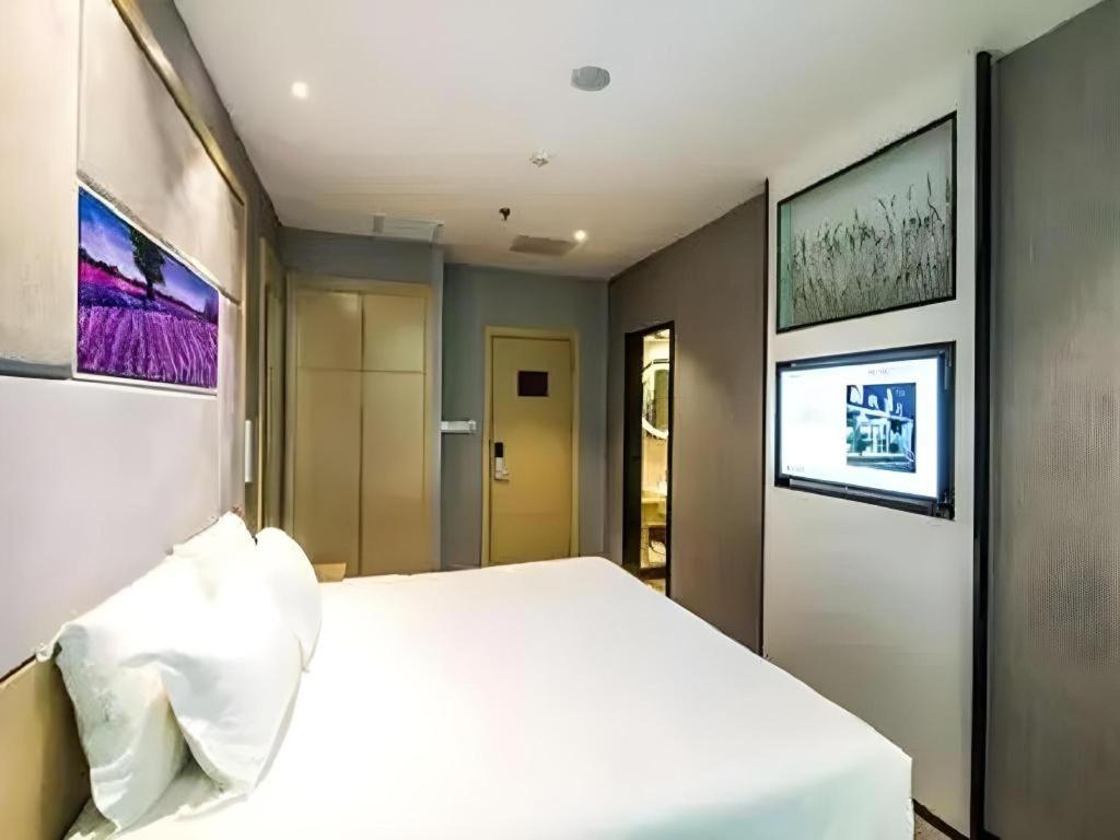 a bedroom with a white bed and paintings on the wall at Zmax Hotel·Yantai Shimao Binhai Plaza in Yantai