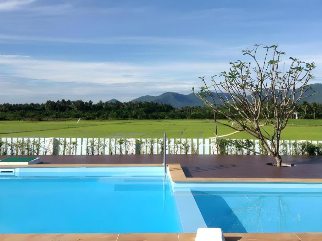 a swimming pool with a tree on a golf course at Juntima Boutique Hotel in Ban Rong Rakam