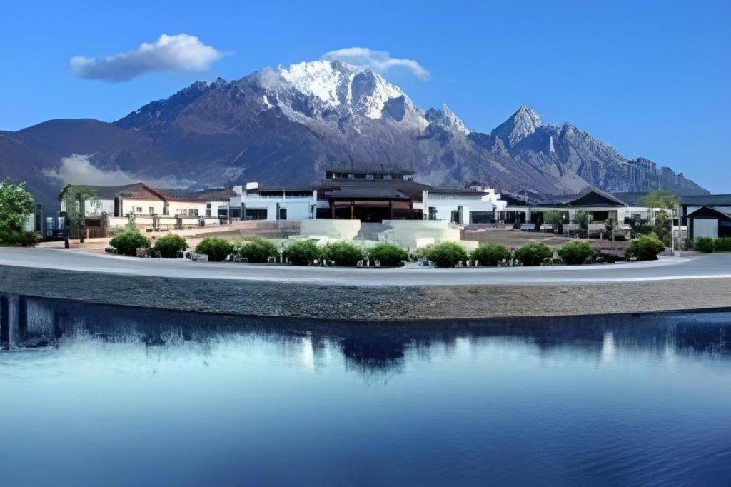 a building with a mountain in the background next to a body of water at Wonderport International Hotel in Lijiang