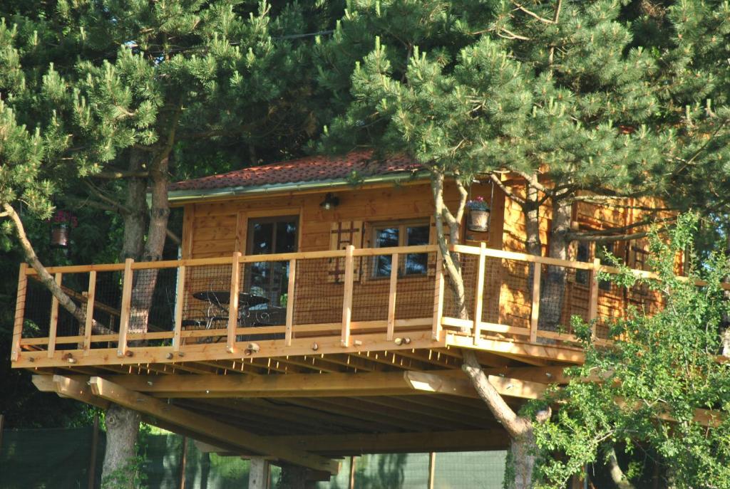 ein Baumhaus mit einer Terrasse in den Bäumen in der Unterkunft L'Etournelle - Cabane Perchée in Chaussan