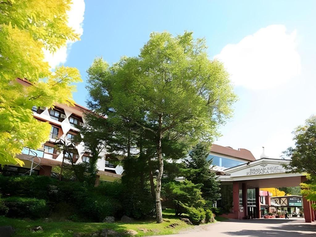 drzewo stoi przed budynkiem w obiekcie Ikenotaira Hotel w mieście Tateshina