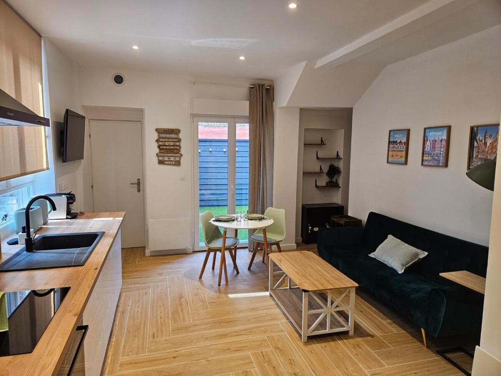 eine Küche und ein Wohnzimmer mit einer Couch und einem Tisch in der Unterkunft Le 325 Appartement de qualité avec terrasse in Béthune