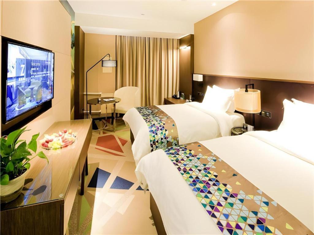 a hotel room with two beds and a flat screen tv at Zmax Hotel·Harbin Bingxue Big World in Harbin