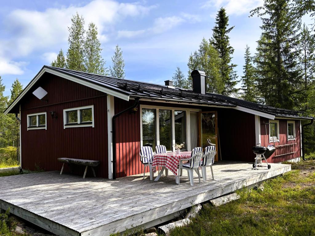 a red cabin with a table and chairs on a deck at Holiday Home Fjätervålen Fjätstigen in Fjätervålen