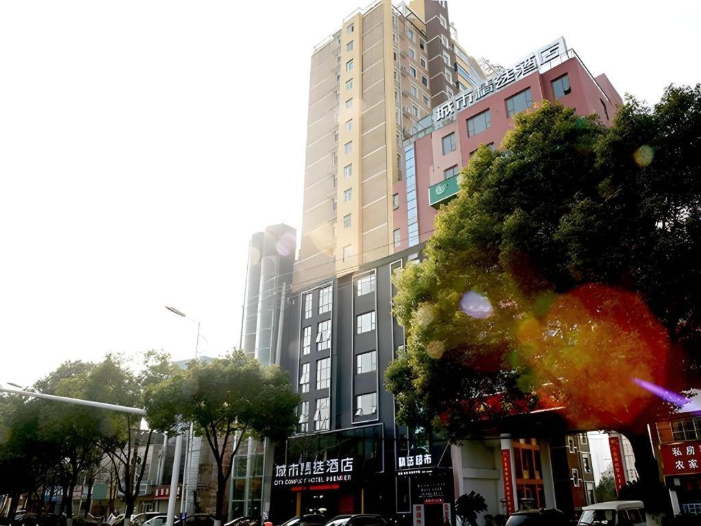 a tall building on a city street with cars at City Comfort Premier Hotel Xiaogan Anlu Railway Station Dongda Times Square in Xiaogan