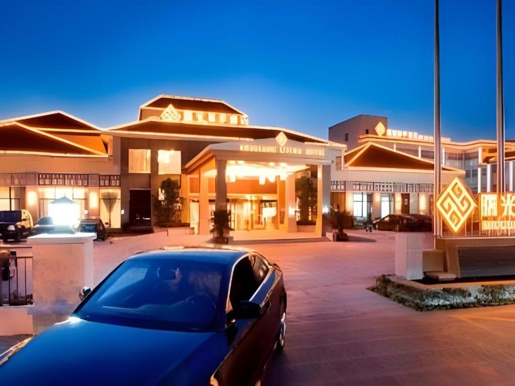 une voiture bleue garée devant un bâtiment dans l'établissement Shuguang Liting Hotel Ningbo, à Ningbo