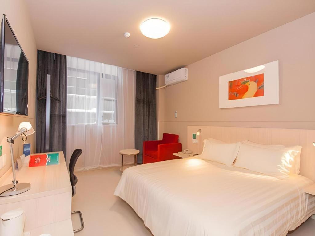 ein Schlafzimmer mit einem weißen Bett und einem roten Stuhl in der Unterkunft Jinjiang Inn Bengbu Huaihe Road in Bengbu