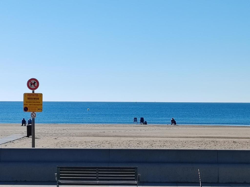 un banc sur une plage avec l'océan en arrière-plan dans l'établissement Studio SAM - Face à la Mer, à Port-la-Nouvelle